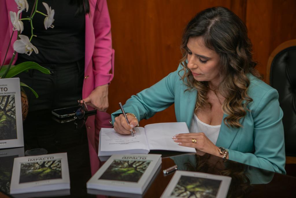Rossana Báez Mendoza firmando ejemplares